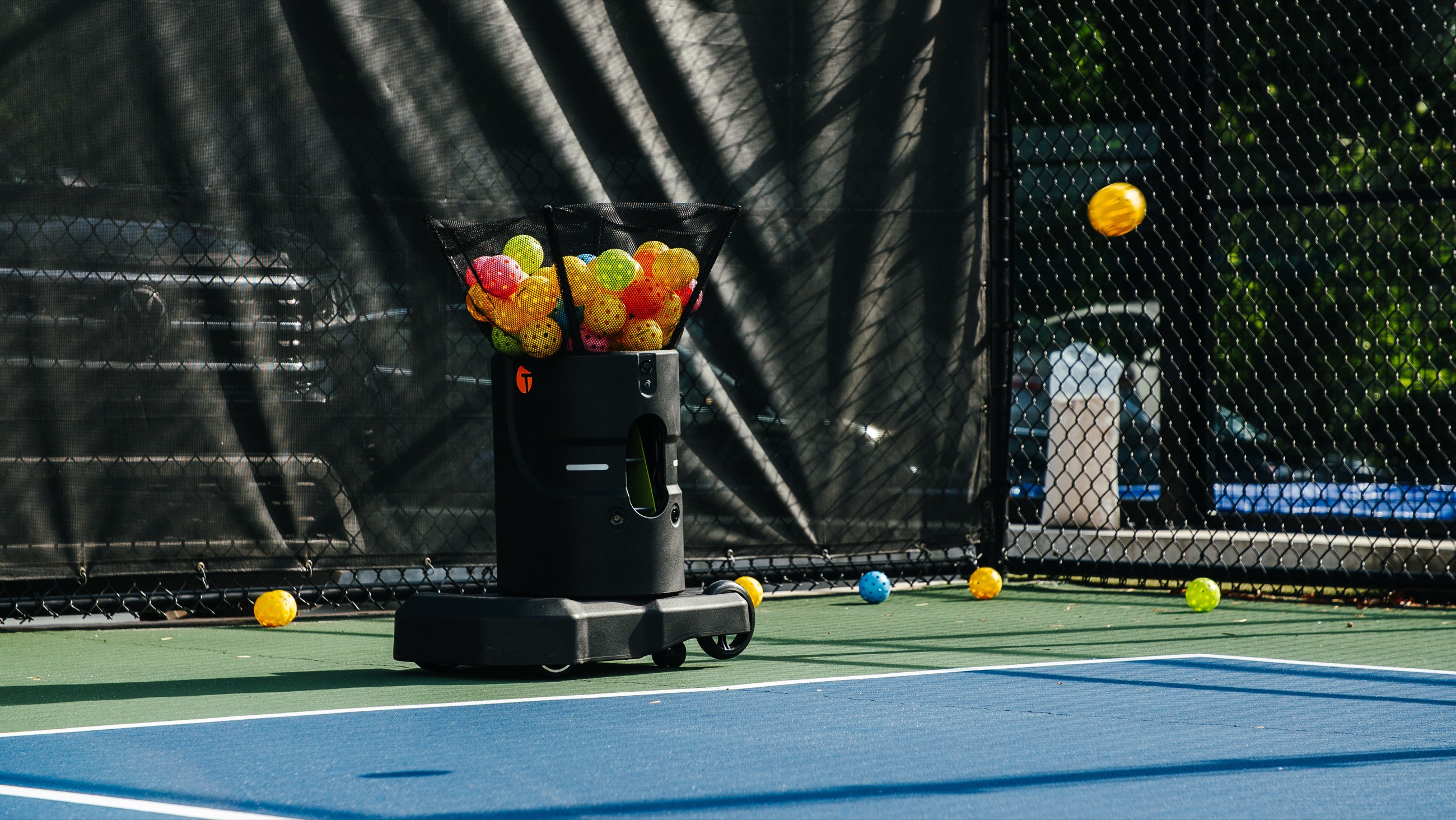 Tennibot Partner pickleball machine loaded with colorful pickleballs on an outdoor court